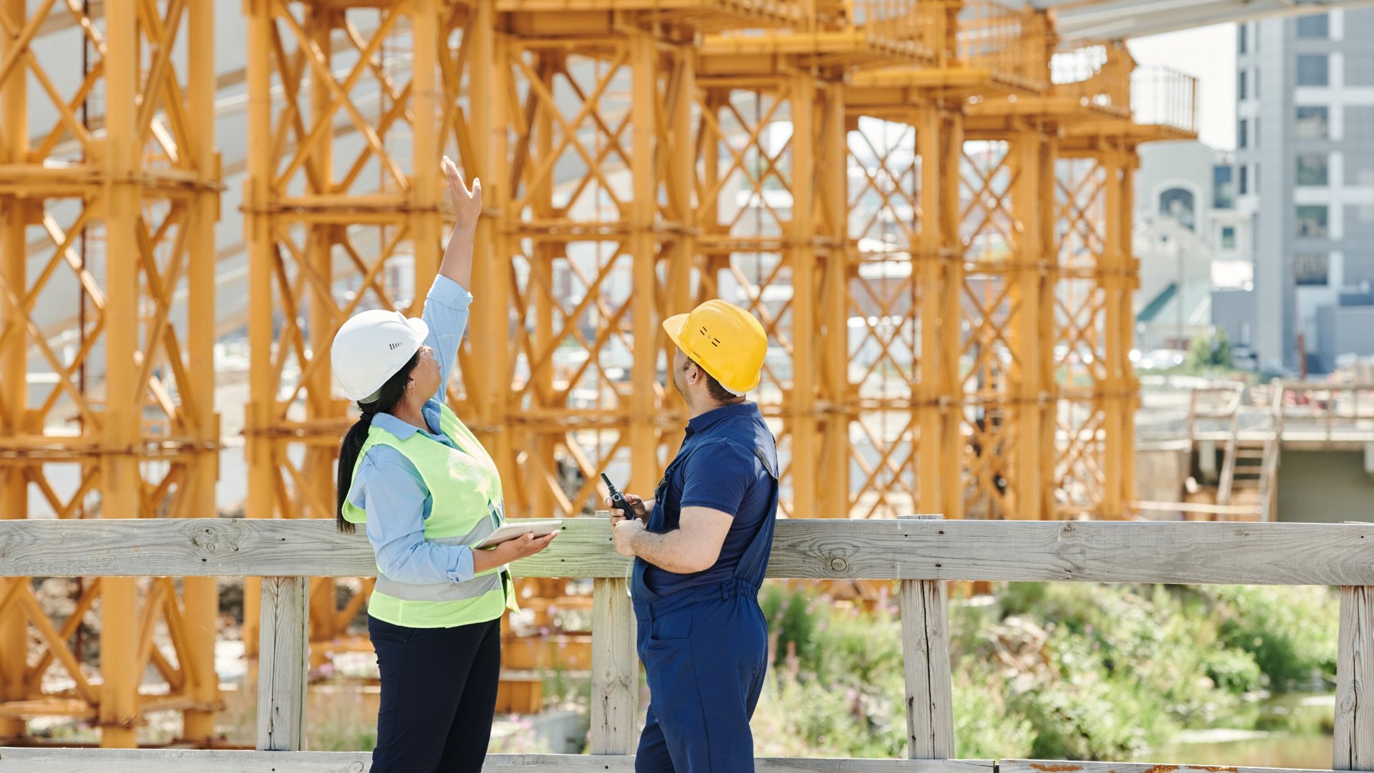 Site supervisor and worker in hard hats reviewing a structure