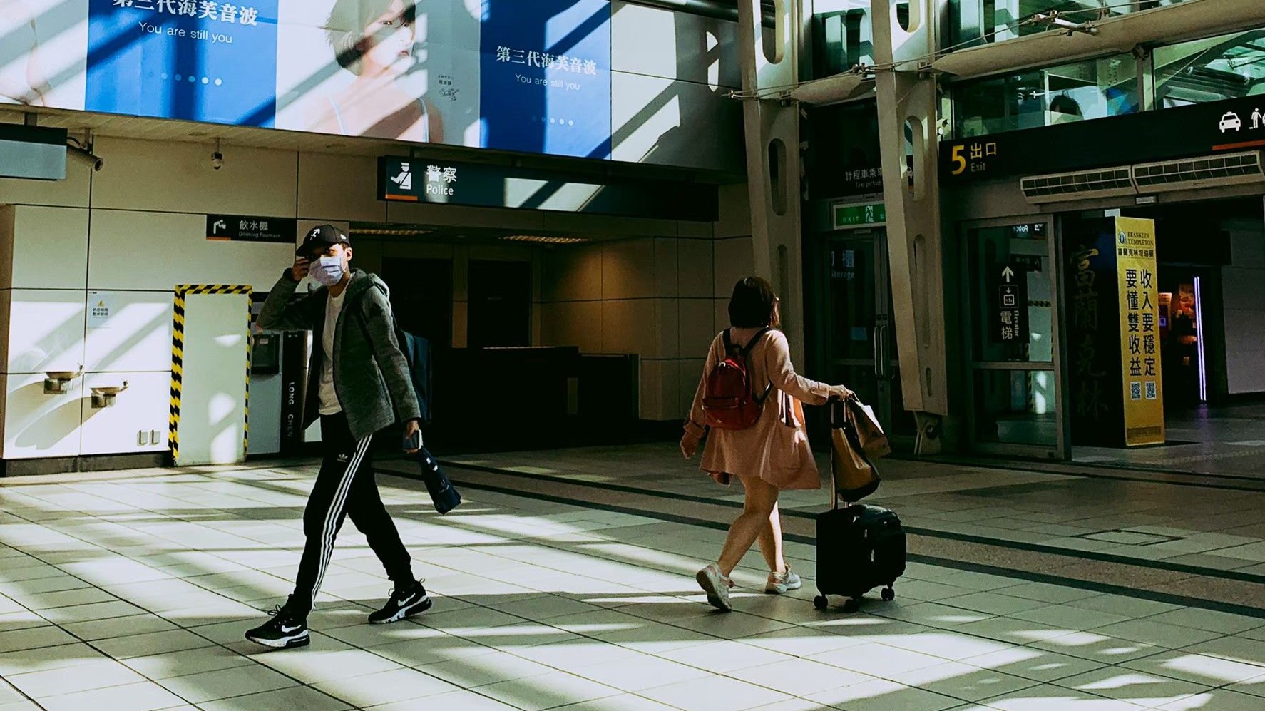 Travellers crossing a sunlit terminal hall
