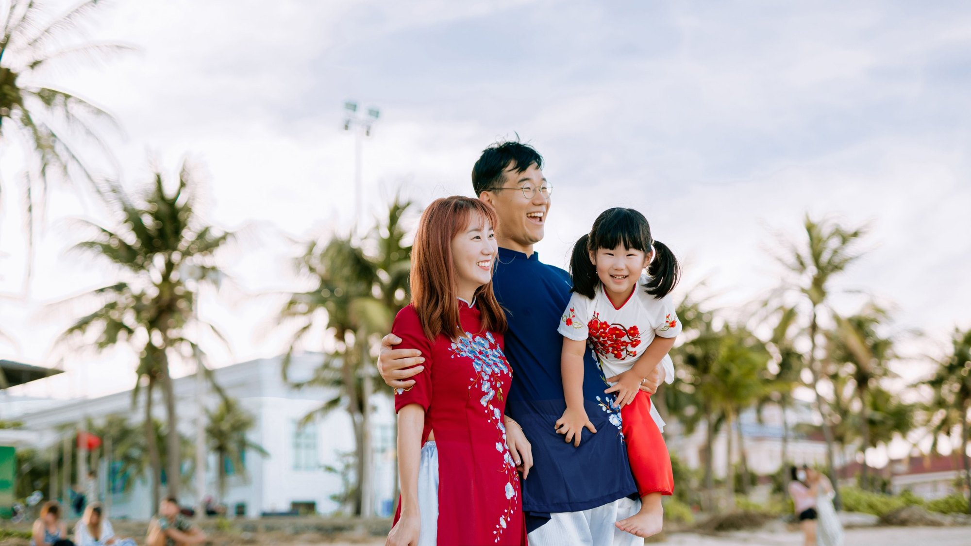 Smiling family of three outdoors under palm trees